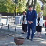 Uroczyste ustawianie płonących zniczy przed pomnikami.