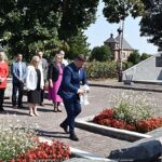 Uroczyste ustawianie płonących zniczy przed pomnikami.