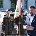 Przemawiający burmistrz w towarzystwie żołnierzy.