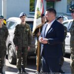 Przemawiający burmistrz w towarzystwie żołnierzy.