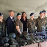 Kilka osób, w tym kobiety w mundurach, stoi w namiocie za stołem.