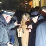 Uroczystość przekazania ognia z Betlejem przed ratuszem. Harcerze, księża i osoby cywilne zapalają łuczywa od ognia.