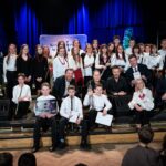 Grupowe zdjęcie na scenie: nagrodzonych artystów, organizatorów i jurorów.