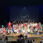 Grupa aktorów pozujących do grupowego zdjęcia na scenie.