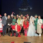 Grupa aktorów pozujących do grupowego zdjęcia na scenie.