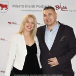 Uśmiechnięci ludzie w trakcie powitania na tle ścianki.