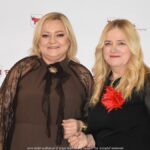 Uśmiechnięci ludzie w trakcie powitania na tle ścianki.