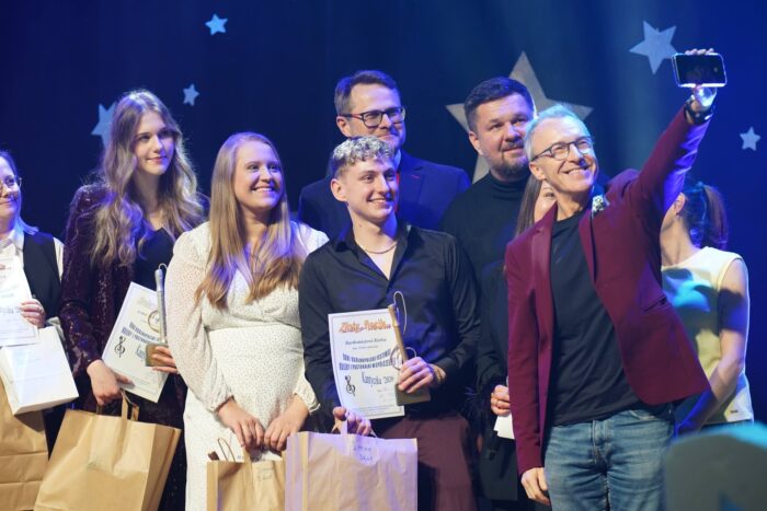 Wręczenie nagród na scenie domu kultury. Artyści robią sobie selfi.