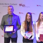 Nagrodzeni sportowcy i ich trenerzy pozują do zdjęcia.