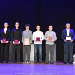 Nagrodzeni sportowcy i ich trenerzy pozują do zdjęcia.