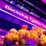 Zdjęcie sceny z perspektywy żaby. Na pierwszym planie bukiet kwiatów, na drugim - napis zawieszony nad sceną "Bielska Gala Sportu".