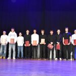 Nagrodzeni sportowcy i ich trenerzy pozują do zdjęcia.