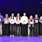 Nagrodzeni sportowcy i ich trenerzy pozują do zdjęcia.