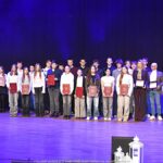 Nagrodzeni sportowcy i ich trenerzy pozują do zdjęcia.