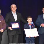 Nagrodzeni sportowcy i ich trenerzy pozują do zdjęcia.