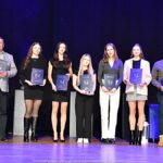 Nagrodzeni sportowcy i ich trenerzy pozują do zdjęcia.