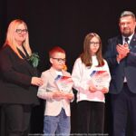 Nagrodzeni sportowcy i ich trenerzy pozują do zdjęcia.