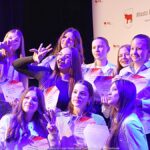 Nagrodzeni sportowcy i ich trenerzy pozują do zdjęcia.