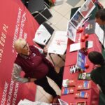 Wystawcy, młodzież i goście podczas prezentacji w liceum.