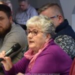 Uczestnicy spotkania rozmawiają siedząc za długim stołem.