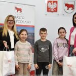 Grupowe zdjęcie nagrodzonych dzieci i nauczycieli ze szkół, w towarzystwie urzędników.