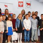 Grupowe zdjęcie nagrodzonych dzieci i nauczycieli ze szkół, w towarzystwie urzędników.