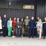 Grupa ludzi przed pojazdem ustawionym na Placu Ratuszowym. Zdjęcie zbiorowe uczestników szkolenia.