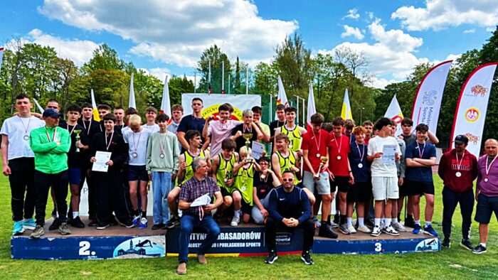 Grupa młodych sportowców na podium.