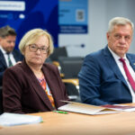 Samorządowcy i uczestnicy spotkania siedzący za stołem.