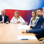 Samorządowcy i uczestnicy spotkania siedzący za stołem.