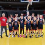 Zdjęcie drużyny koszykarskiej na hali sportowej.