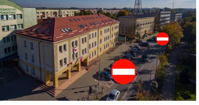 Ulica w centrum miasta, przed urzędem miasta, ujęcie z lotu ptaka. Na nim nałożone dwa znaki drogowe - zakazy wjazdu.