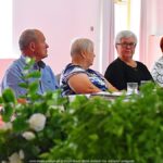 Na 1. planie zielenina, na 2. planie - uczestnicy spotkania.