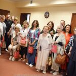 Wizyta artystów u burmistrza. Zdjęcie grupowe - kilkanaście osób uśmiecha się i pozuje do zdjęcia.