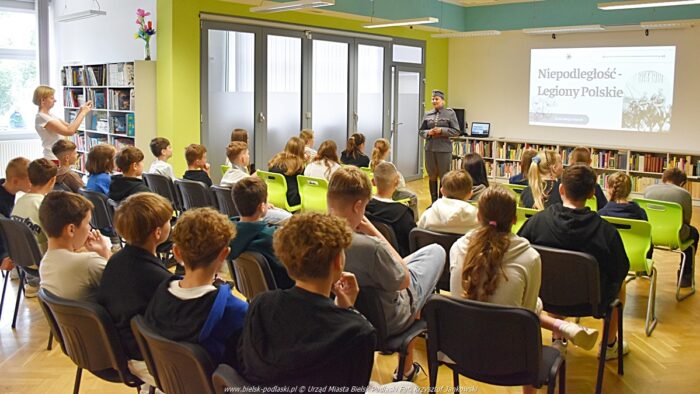 Młodzież siedząca na krzesłach podczas wykładu w bibliotece.