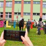 Młodzież przed biblioteką podczas oglądania pokazu koni.