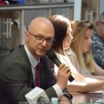 Spotkanie grupy osób dorosłych w sali konferencyjnej urzędu miasta.