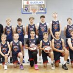 Zdjęcie drużyny koszykarskiej na hali sportowej.