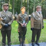 zdjęcie przedstawia 4 żołnierzy, druga od lewej stoi kobieta w mundurze trzymająca znicz