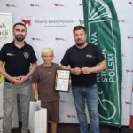 Zdjęcie uczestnika rywalizacji z Dyrektorem MOSiR i Burmistrzem Miasta Bielsk Podlaski na tle banerów